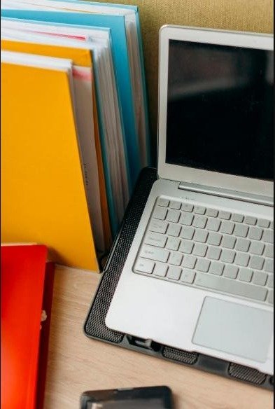 A neat office setup featuring a laptop, colourful files, and a tidy desk arrangement.