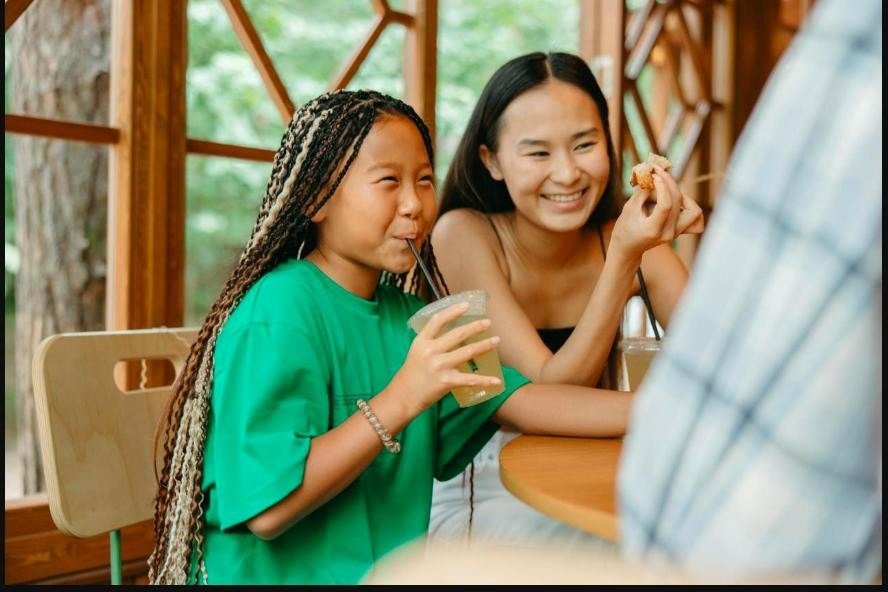 A mother and daughter enjoying a fun meal together in a bright café with wooden interior.